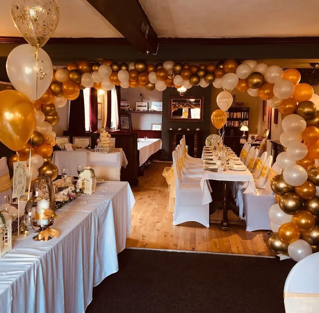 The dining room set for a celebration, framed by a gold balloon arch