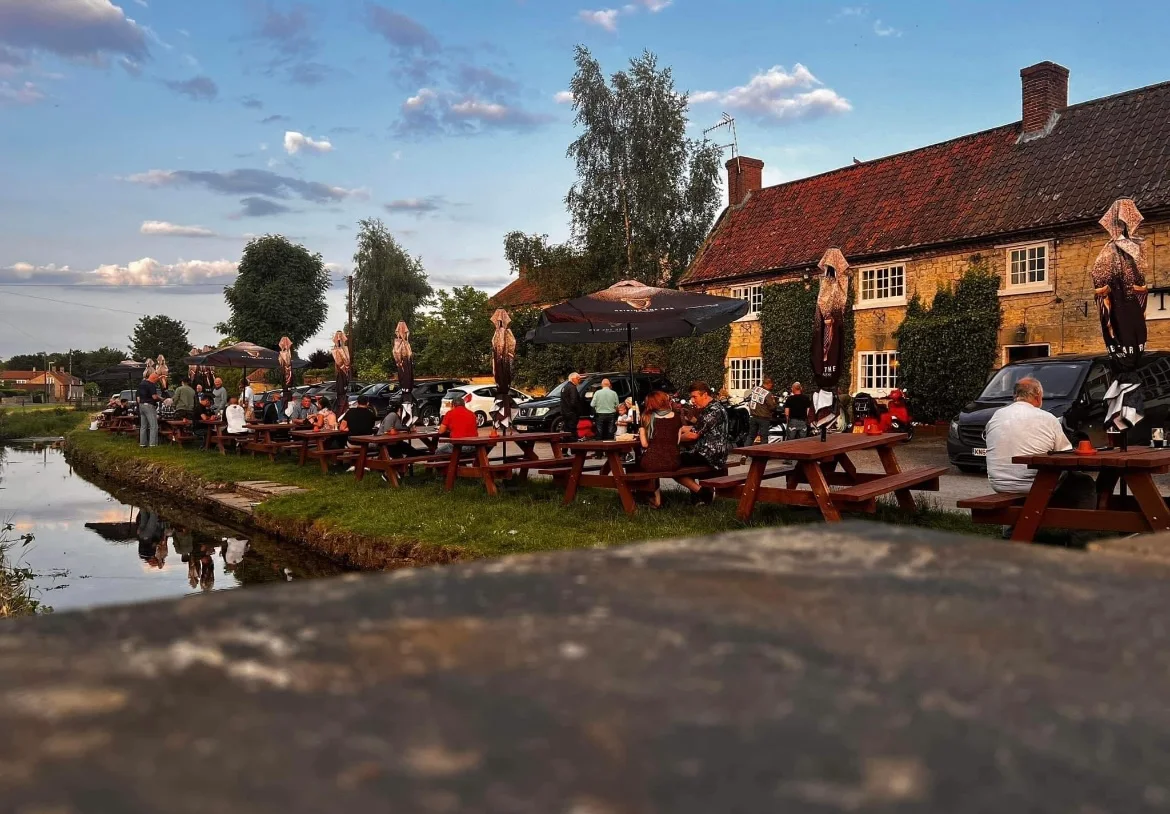 The Royal Oak's stone frontage at golden hour, with picnic benches along the beck that runs through Scopwick